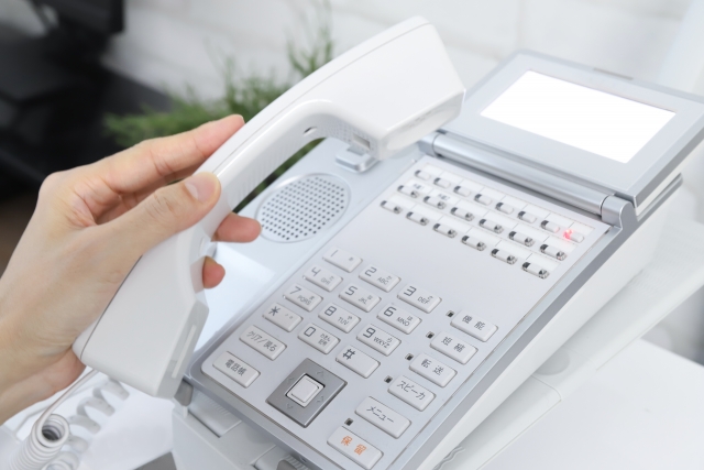 固定電話の受話器を持つ手